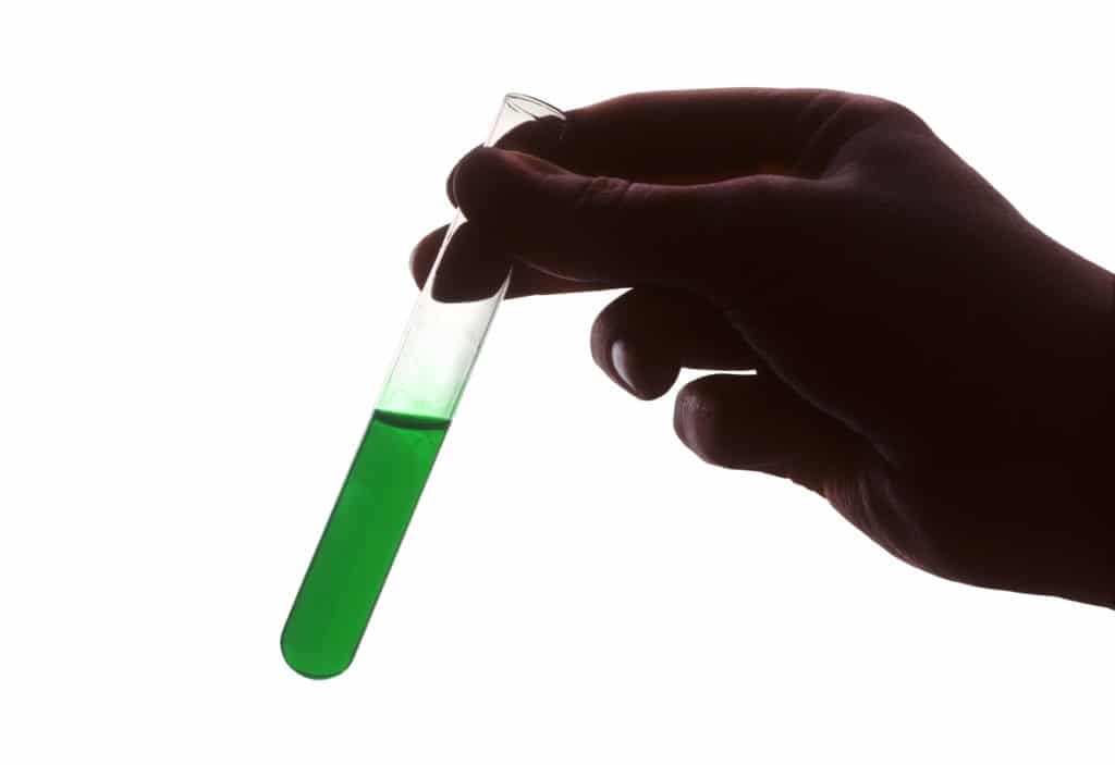 Hand holding test tube of green liquid-Biology Classes