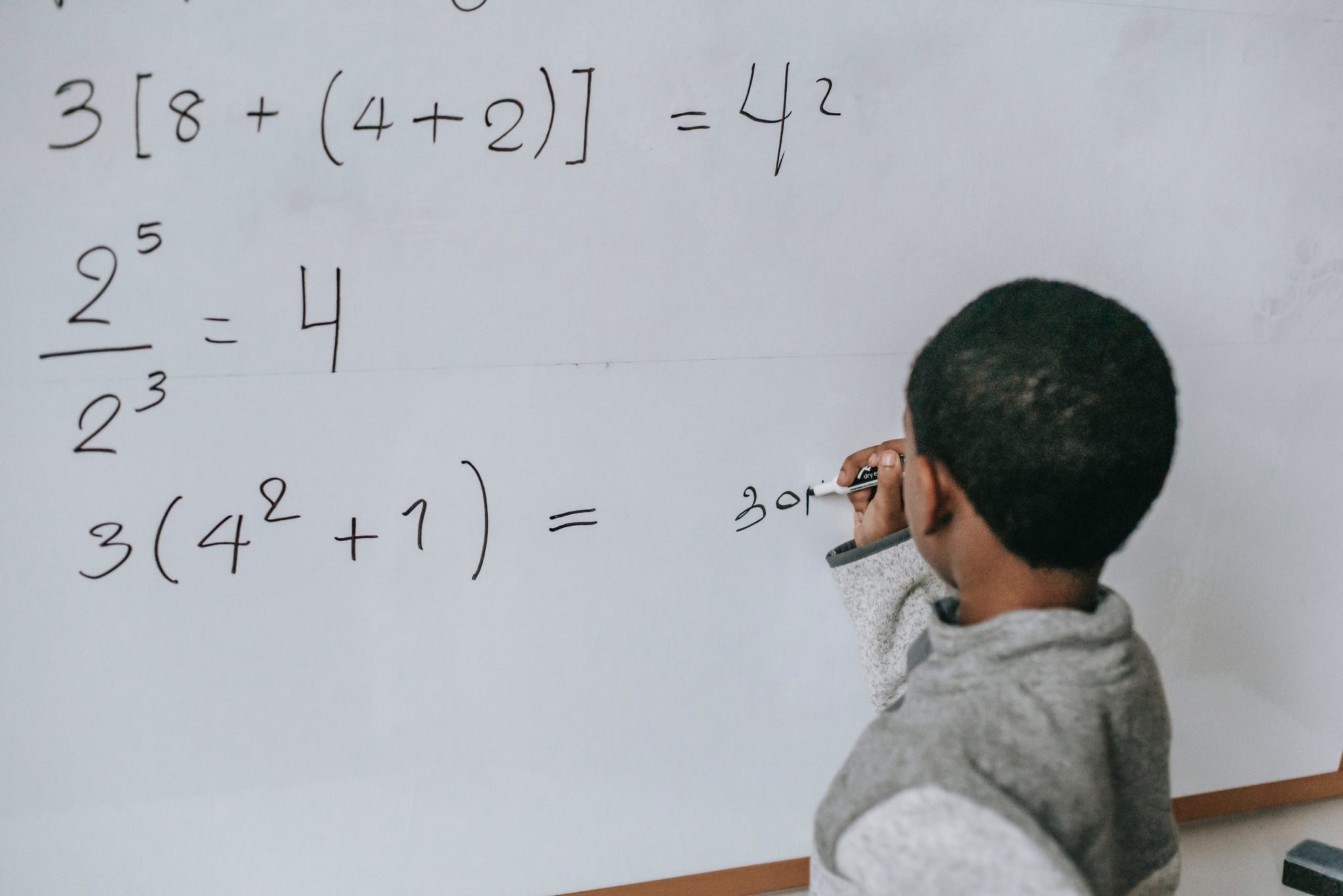 photo of a boy writing maths on white board-maths classes-online super tutors